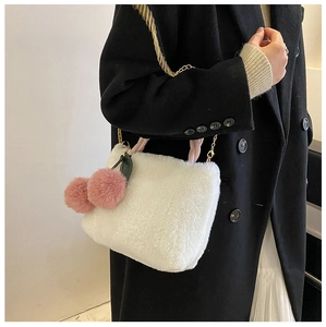Detail of white faux fur bucket bag with pink cherry pom-poms and gold chain strap