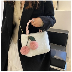 Detail of white faux fur bucket bag with pink woven handles and cherry plush charm
