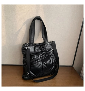 Detail of black puffer tote bag showing quilted nylon texture and adjustable shoulder strap