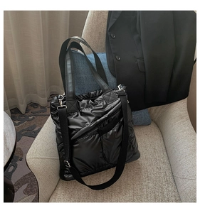 Detail of black quilted puffer tote bag with side zipper and nylon glossy texture