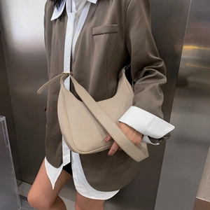 Chic beige dumpling underarm bag with adjustable strap shown in a modern urban setting