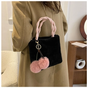 Detail of plush black bag featuring pink woven handle and cute cherry charms on side
