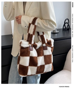 Brown and white checkerboard plush tote bag shown with model in a modern interior setting