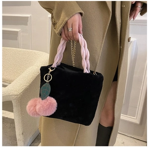 Detail of plush black faux fur bucket bag with pink braided handle and cherry charms