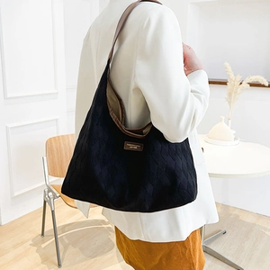Grand sac cabas noir matelassé avec anses en cuir marron porté par un mannequin en studio