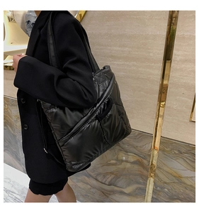 Close-up of black quilted puffer tote bag in glossy nylon with functional pockets