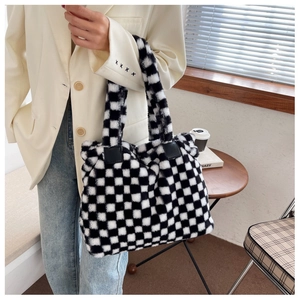 Detail view of black and white checkerboard plush tote bag styled with casual blazer and jeans