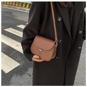 Close-up of caramel brown saddle bag with metal bar buckle and adjustable strap