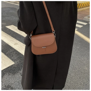 Outdoor shot showing back view of vintage brown saddle bag with silver hardware on black coat