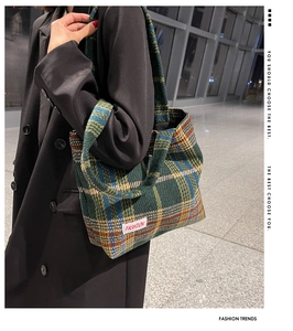 Detailed view of the green plaid wool tote bag with a white FASHION woven label
