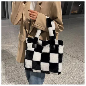 Fuzzy checkerboard laptop tote bag carried by model in a stylish beige suit and jeans