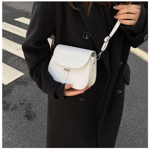Close-up of white minimalist saddle bag with silver buckle worn on black wool coat