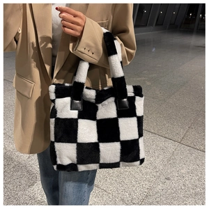 Detail of soft black and white checkered plush tote bag with leather reinforced handles