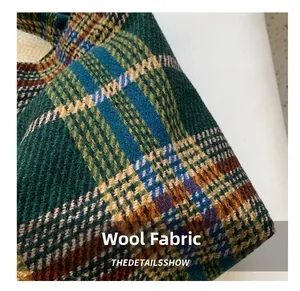 Close-up of premium green and brown plaid woolen fabric showing textured twill weaving