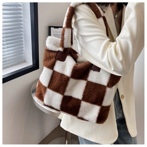 Detail of checkered plush tote bag featuring leather reinforcement and soft faux fur texture