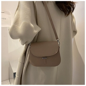 Side view of a vintage beige saddle bag with a silver buckle and slim shoulder strap