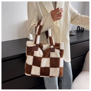 Detail of brown checkered plush tote bag with reinforced leather handle attachment