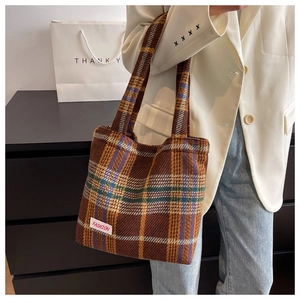 Detailed view of brown plaid woolen tote bag with a fashion label and stylish twin handles
