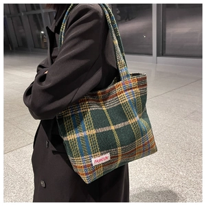 Detail shot of a plaid woolen tote bag with a fashion label on a minimalist indoor setting