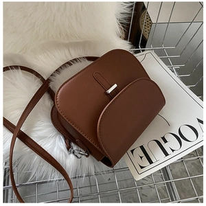 Detailed macro view of a brown matte leather saddle bag with rectangular silver buckle