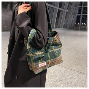 Detail of colorful tweed plaid tote bag with FASHION label worn by a model