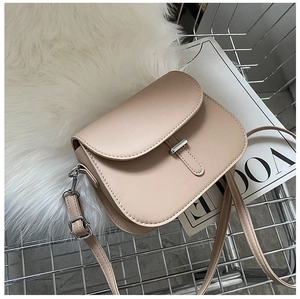 Detail of beige saddle bag with silver buckle on faux fur and fashion magazine background