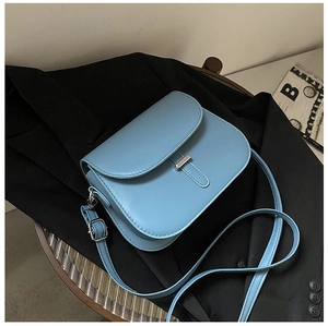 Detail of blue matte leather saddle bag with silver buckle on a black blazer jacket