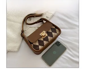 Detail of vintage plaid saddle bag with leather strap and metal buckle beside a phone