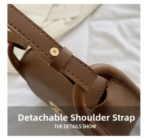Detail of the detachable leather shoulder strap with gold hardware on brown saddle bag