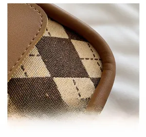 Macro detail of retro plaid fabric texture and brown leather stitching on shoulder bag