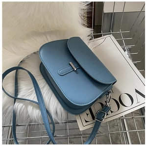 Blue leather saddle bag on faux fur with fashion magazine and silver hardware detail