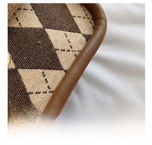 Detailed macro view of retro brown argyle fabric and premium leather edge stitching