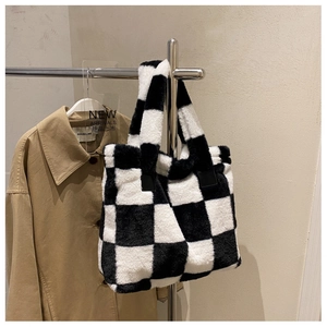 Detail of checkered plush laptop tote bag with soft faux fur texture on a display stand