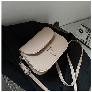 Detail of beige leather saddle bag with silver metal trim on a black blazer jacket