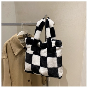 Detailed close-up of a black and white checkerboard plush tote bag on a metal hanger