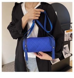 Close-up of klein blue quilted nylon cylinder bag with adjustable shoulder strap