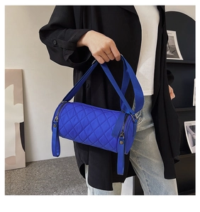 Detail of blue quilted nylon bucket bag with wide shoulder strap worn by a model