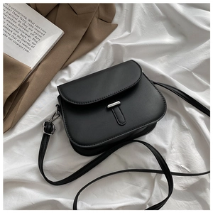 Close-up of black matte saddle bag with silver buckle on elegant fabric