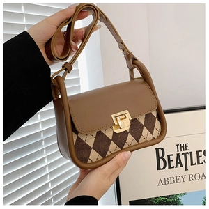 Detail of the brown checkered saddle bag featuring a gold metal buckle and leather flap