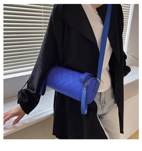 Close-up of blue quilted cylinder crossbody bag featuring nylon texture and wide strap