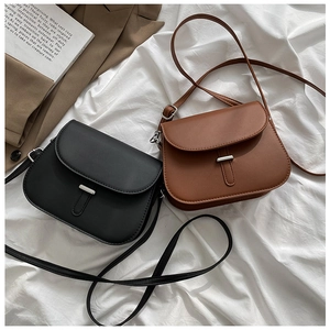 Close-up of minimalist black and brown crossbody saddle bags with silver metal buckles