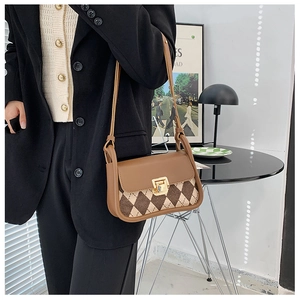 Close-up of vintage brown checkered saddle bag with gold buckle and leather strap detail