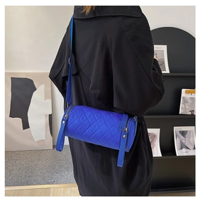 Detailed back view of a blue quilted cylinder crossbody bag on a female model