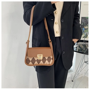 Detail of vintage plaid saddle bag with brown leather flap and golden metal buckle