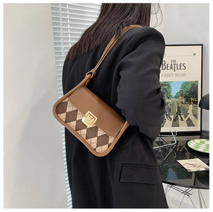 Close-up of retro brown plaid saddle bag with golden metal buckle and argyle pattern