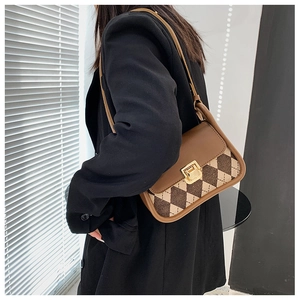 Detail of vintage plaid saddle bag with golden clasp worn by a model in a black blazer
