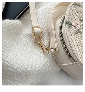 Detailed close-up of light gold metal hooks and textured off-white woven straw bag