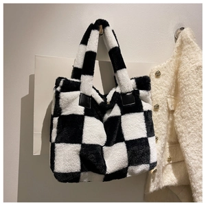 Close-up of black and white checkerboard plush laptop bag with leather handle detail