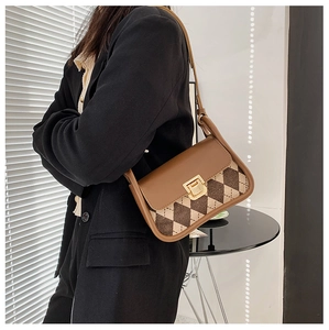 Side view of woman wearing a vintage plaid saddle bag with brown leather and gold lock