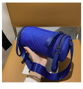 Detailed close-up of quilted blue nylon bucket bag with dual zippers and woven strap